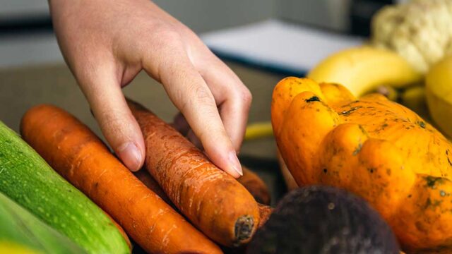 womans-hand-sorting-carrots-and-onions