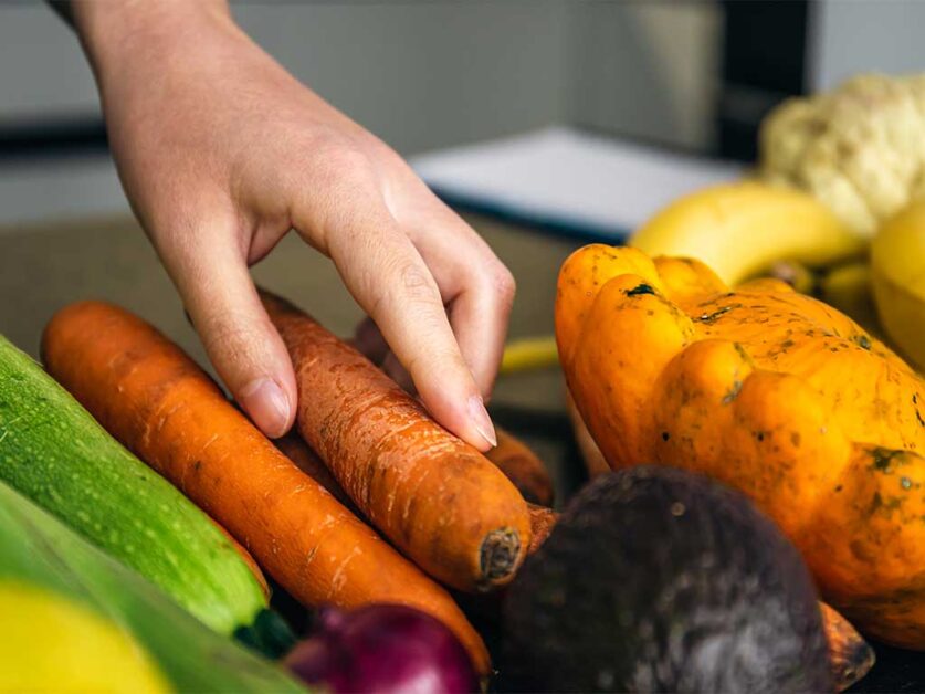 womans-hand-sorting-carrots-and-onions